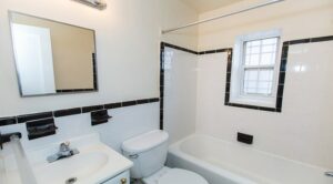 bathroom with tub, toilet, vanity, mirror and window at 4031 davis place apartments in glover park washington dc