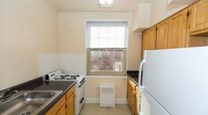 kitchen with oak cabinets, gas range, refrigerator and large window at 1401 sheridan apartments in washington dc