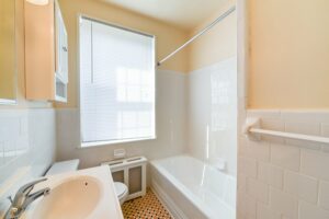 bathroom with tub, vanity, medicine cabinet, toilet and large window at 1401 sheridan apartments in washington dc