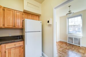 kitchen with oak cabinets, refrigerator and view of dining area at 1401 sheridan apartments in washington dc