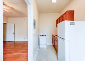 view of kitchen with gas range and vacant living area with ceiling fan and hardwood floors at 1818 Riggs place apartments in washington dc