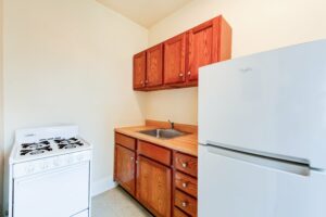 kitchen with refrigerator, gas range and wood cabinets at 1818 Riggs place apartments in washington dc