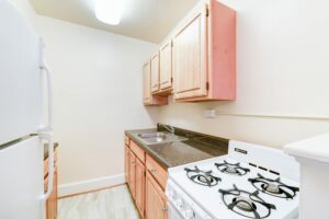 kitchen with fridge, gas range, and wood cabinets at 4031 davis place apartments in glover park washington dc