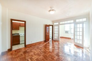 vacant living area with hardwood floors, view of kitchen and view of sunroom with large windows at the eddystone apartments in washington dc