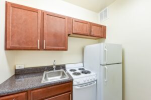 kitchen with wood cabinets, fridge, and electric stove at the eddystone apartments in washington dc