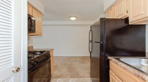 kitchen with refrigerator, gas range and view of living area at grandview village apartments in shipley terrace washington dc