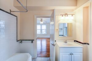 bathroom with tub, vanity, mirror and view of bedroom with hardwood floors and ceiling fan at hampton courts apartments in washington dc