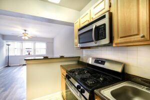 kitchen with stainless steel appliances, breakfast bar and view of living area at hilltop house apartments in columbia heights washington dc