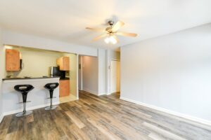 open layout of apartment showing living area, kitchen and breakfast bar with hardwood floors and ceiling fan at hilltop house apartments in columbia heights washington dc