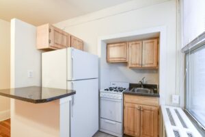 kitchen with refrigerator, gas range, breakfast bar and wood cabinets at the cortland apartments in adams morgan washington dc