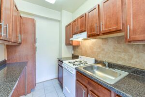 kitchen with modern cabinetry, gas range, sink and tile backsplash at the klingle apartments in cleveland park washington dc