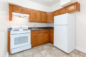 kitchen with oak cabinetry, tile flooring, gas range and white appliances at 1400 van buren apartments in washington dc