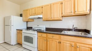 kitchen with gas range, refrigerator, wood cabinetry and tile backsplash at the calverton apartments in adams morgan washington dc