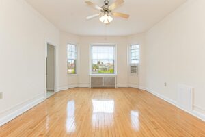 vacant living area with hardwood floors, ceiling fan and large windows at the calverton apartments in adams morgan washington dc