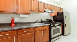 kitchen with stainless steel appliances, gas range, wood cabinetry and tile backsplash at the calverton apartments in adams morgan washington dc