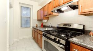 kitchen with stainless steel appliances, wood cabinetry, gas range, window and tile backsplash at the calverton apartments in adams morgan washington dc