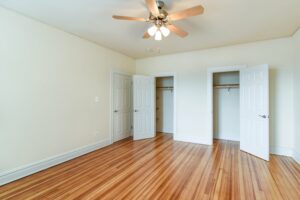vacant bedroom with large closets, ceiling fan and hardwood floors at 2701 Connecticut apartments in washington dc