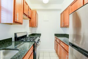 kitchen with stainless steel appliances, wood cabinetry and gas range at 2800 woodley road apartments in washington dc
