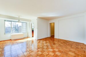 vacant living area with wood floors and large windows at 2800 woodley road apartments in washington dc