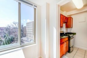 large window with view of kitchen with stainless steel appliances, wood cabinets and gas range at 2800 woodley road apartments in washington dc
