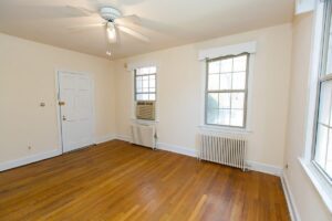 vacant living area with hardwood floors, ceiling fan and large windows at 4020 Calvert street apartments in washington dc