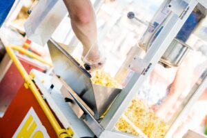 A person uses a popcorn machine to scoop popcorn into a bag, savoring the delicious aroma that fills their stylish DC apartment. | DC Apartments by WC Smith