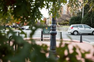 View of a "City of Takoma Park" sign surrounded by foliage, situated near a road with cars and buildings in the background, just minutes away from popular DC apartments. | DC Apartments by WC Smith