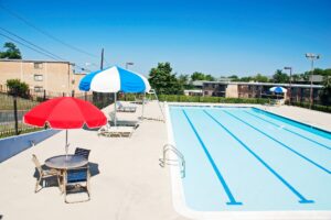 swimming pool and deck with tables, chairs and umbrellas at washington view apartments in washington dc