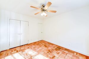 vacant bedroom with hardwood floors, closet and ceiling fan at 2800 woodley road apartments in washington dc