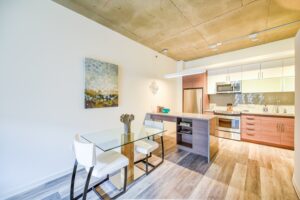 modern kitchen with stainless steel appliances, tile backsplash, kitchen island and dining area at the agora at the collective apartments in the capital riverfront washington dc