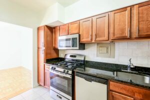 kitchen with stainless steel appliances, gas range, wood cabinetry, tile backsplash and view of dining area at clarence house apartments in washington dc