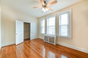 vacant bedroom with hardwood floors, closet, ceiling fan and large windows at the norwood apartments in washington dc