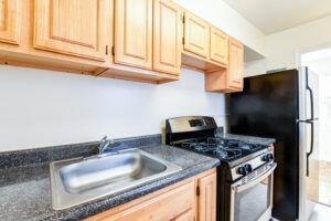 kitchen with stainless steel appliances, gas range and wood cabinetry at richman apartments in congress heights washington dc