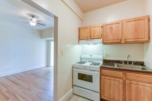 kitchen with gas range and view of living area with wood floors and ceiling fan at twin oaks apartments in petworth washington dc