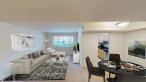 living area with sofa, coffee table, large window, tv, credenza and view of dining area and kitchen at cambridge square apartments in bethesda maryland