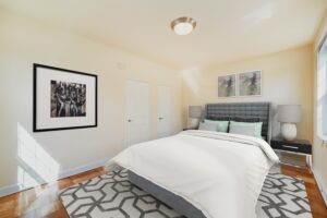 bedroom with bed, nightstands, hardwood floors and large windows at 1401 sheridan apartments in washington dc