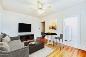 open layout of apartment showing living and dining area with ceiling fan, hardwood floors and view of kitchen at 1818 Riggs place apartments in washington dc