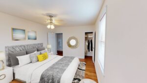bedroom with bed, nightstands, sitting area, hardwood floors and ceiling fan at 6100 14th street apartments in brightwood washington dc
