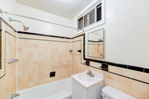 bathroom with tub, vanity, mirror, toilet and window at vacant sun room with exposed brick wall and large windows at 2629 39th Street apartments in washington dc