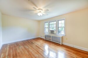 vacant living area with hardwood floors, ceiling fan and large windows at 2629 39th Street apartments in washington dc