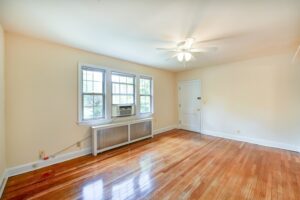 vacant living area with wood floors, ceiling fan, large windows and view of front entrance at 2629 39th Street apartments in washington dc