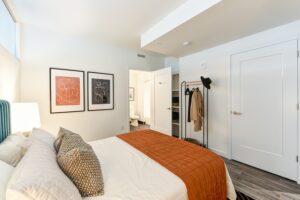 bedroom with bed, nightstand, closet, clothing rack and view of bathroom at the garrett apartments at the collective in washington dc