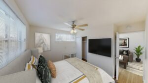 bedroom with large windows, ceiling fan and view of living area at pleasant hills apartments in washington dc