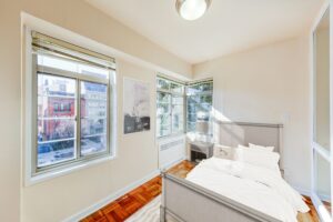 sunroom with bed, nightstand, wood floors and large windows at the baystate apartments in dupont circle washington dc