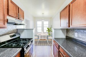 kitchen with wood cabinetry, gas range, tile backsplash and view of dining area at the frontenac apartments in van ness washington dc
