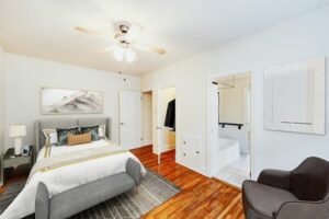 bed with bed, nightstand, sitting area, large closet, hardwood floors and view of bathroom at hampton courts apartments in washington dc