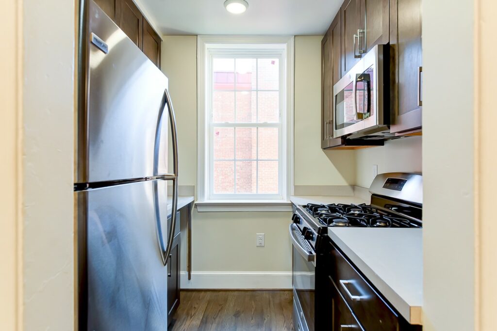 kitchen with stainless steel appliances, gas range, window and espresso cabinetry at petworth station affordable tax credit apartments in washington dc