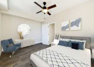 bedroom with bed, nightstands, dresser, sitting area, wood floors and ceiling fan at petworth station apartments in washington dc