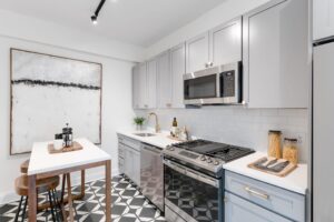 kitchen with stainless steel appliances, modern cabinetry, tile backsplash and small dining area at the dahlia apartments in washington dc