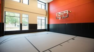 Indoor half basketball court with high windows, red and black walls, and a hoop. | DC Apartments by WC Smith